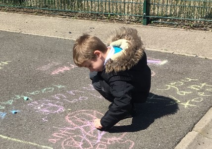 A pupil drawing on the playground with chalk.
