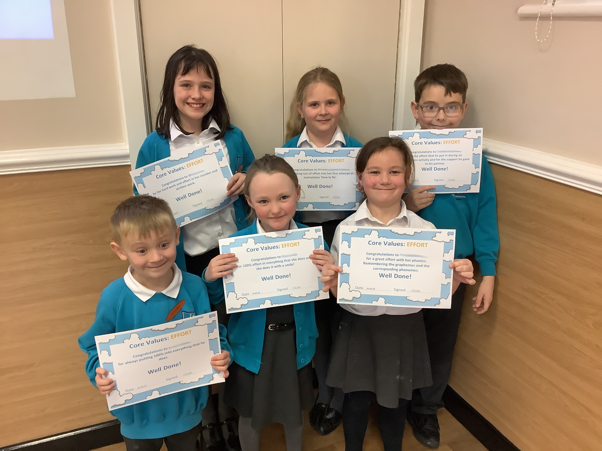Six pupils hold up their 'Core Values: Effort' certificates.